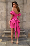 woman looking over shoulder wearing Emiliee hot pink dress