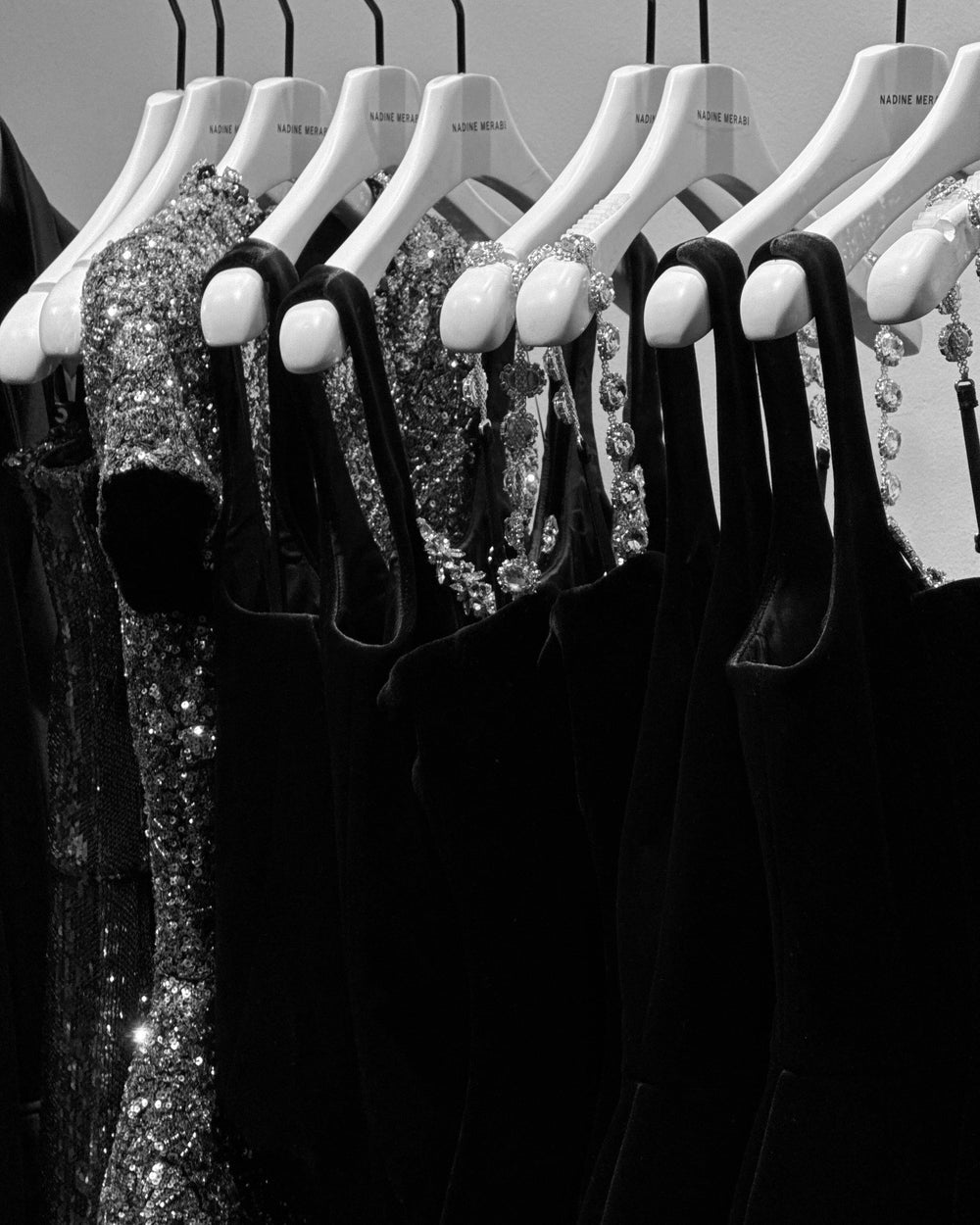 Black and silver sequin dresses on hangers against a neutral background