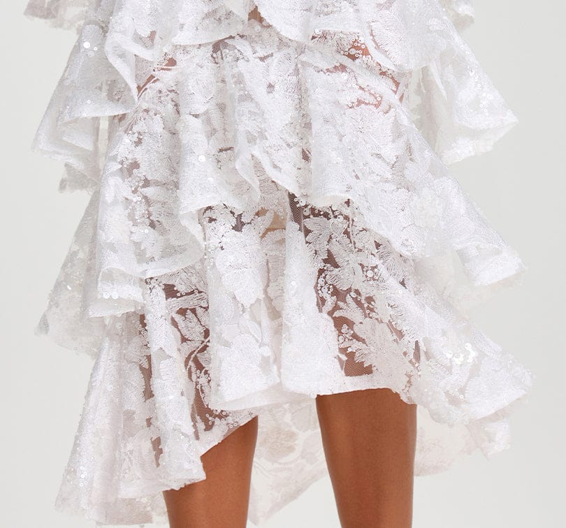 White lace dress with ruffled layers on a white background