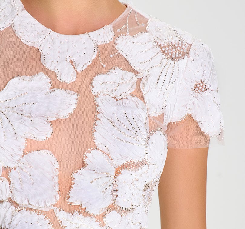 Close-up of a white lace garment with floral patterns on a plain background