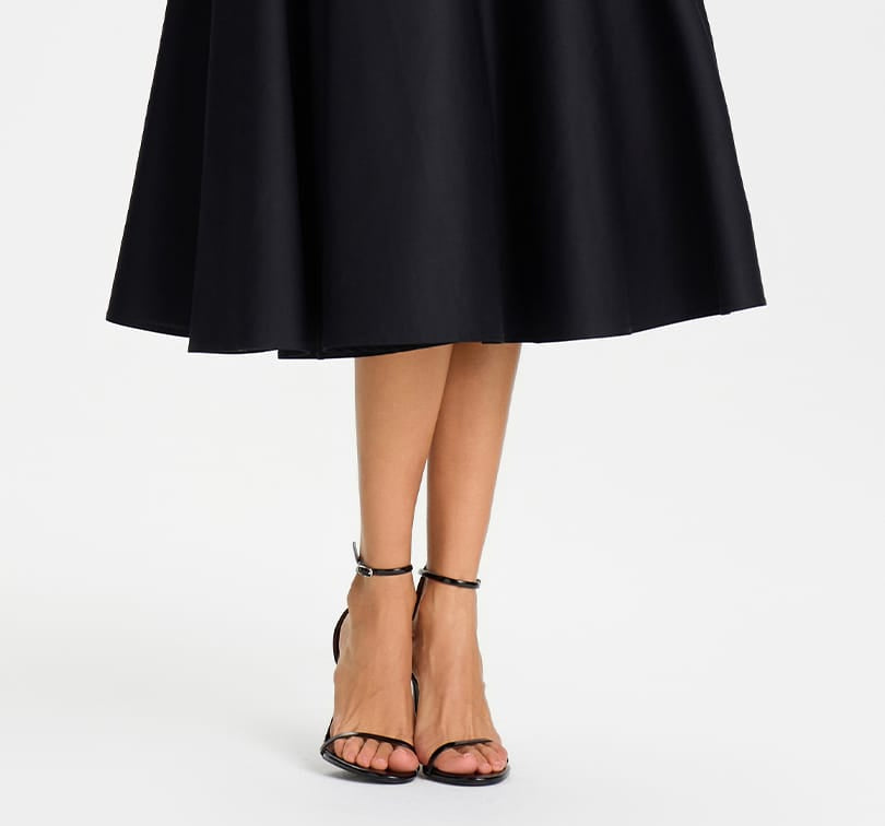 Black knee-length skirt worn by a person on a white background