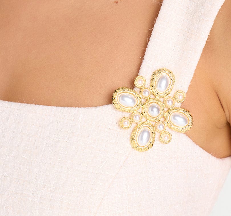 Gold brooch with pearl-like stones on a white garment