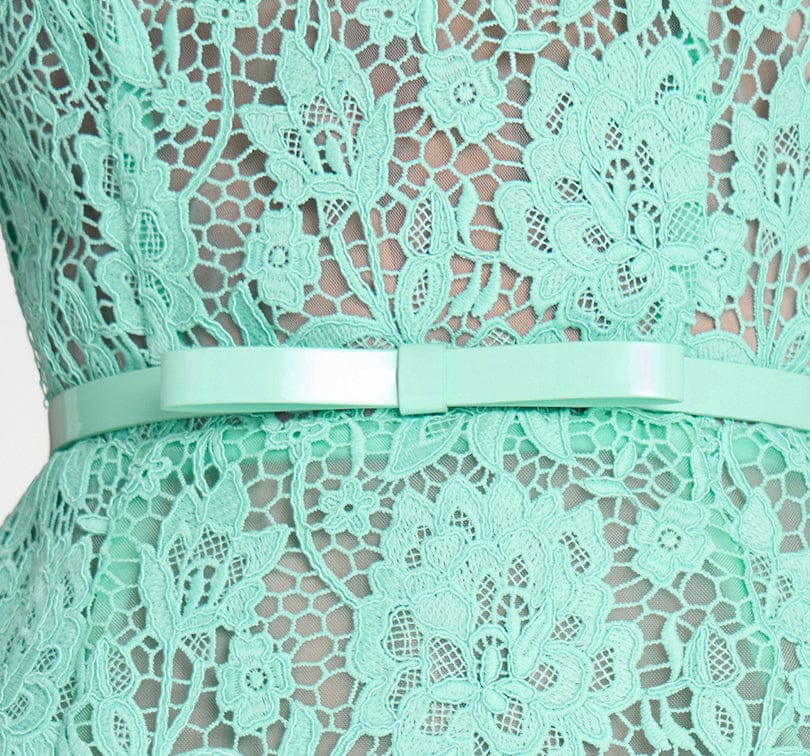 Close-up of a mint green lace dress with a belt on a white background