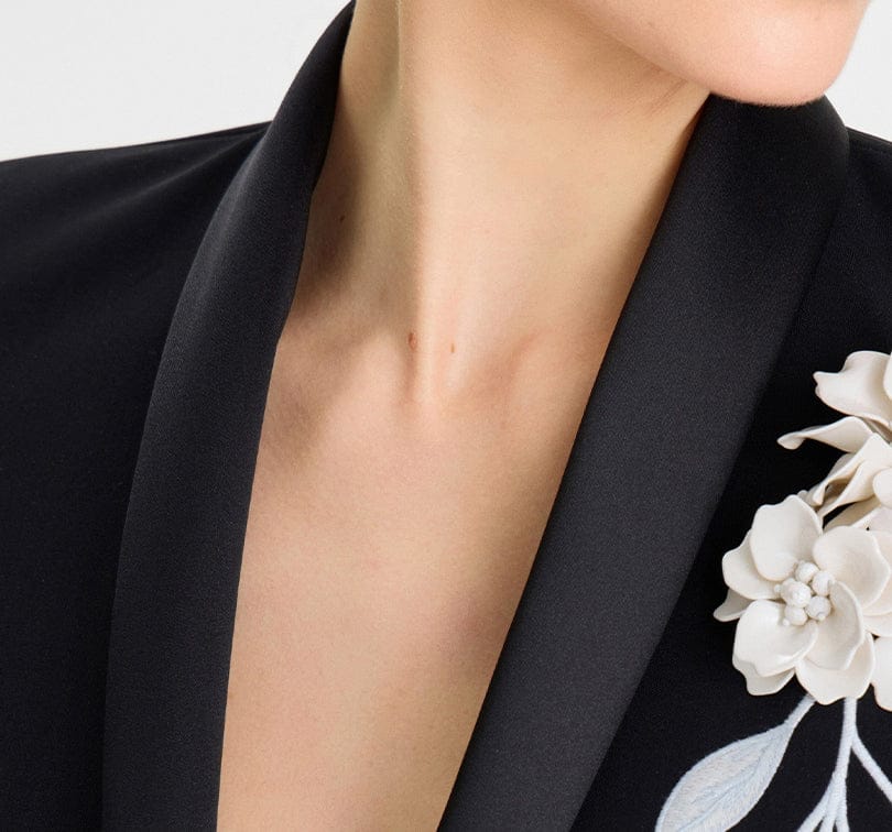 Close-up of a person wearing a black garment with floral embroidery.