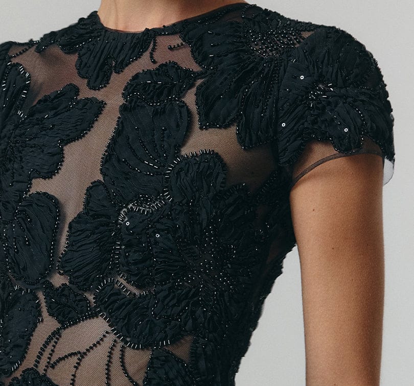 Black embroidered dress with floral patterns on a plain background