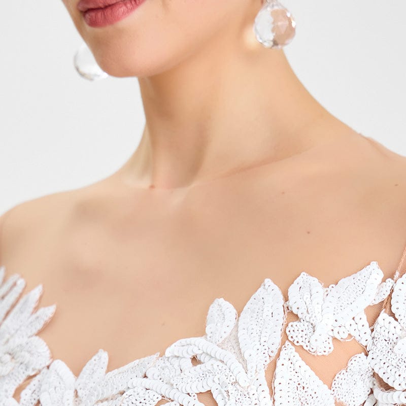 Close-up of a person wearing a white lace garment with a plain background
